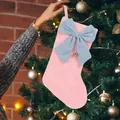 Detail of a plush pink Christmas stocking with a blue bow and bell hanging on a tree - Pink