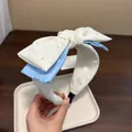 Dettaglio di un cerchietto fatto a mano con fiocco e strass luccicanti - Bianco