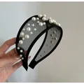 Primo piano di un'elegante fascia in rete nera decorata con perle bianche di varie dimensioni - Cerchietto in Maglia Nera con Perle