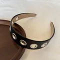 Dettaglio ravvicinato di un cerchietto in pelle nera con occhielli in metallo argento - Nero