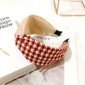 Detailed view of a red and beige houndstooth knotted headband on stylish magazines - Houndstooth Cross Knot / Beige Red