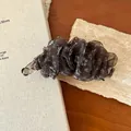 Primo piano di un fermaglio a banana con fiori e volant su un sottobicchiere in pietra. - Floreale Caffè Pieghettato