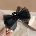 Primo piano di un elegante fermaglio per capelli con fiocco in tulle nero tenuto in mano - Molla per Capelli con Fiocco in Tulle Nero / Molla per Capelli Tinta Unita
