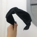 Primo piano di una fascia annodata nera con eleganti cuciture bianche a contrasto, moda. - Stile Nodo Incrociato Largo con Cuciture a Contrasto / Nero