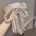 Primo piano di un fermaglio a fiocco color champagne con lunghi nastri e perle - Fiocco a Nastro Lungo (C1-09) / Stile Perla Albicocca