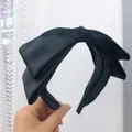 Primo piano del cerchietto in raso nero con fiocco, che mostra la trama elegante. - Modello a fiocco / Nero