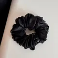 Vue détaillée d'un chouchou en organza noir avec une texture douce et froncée. - Noir