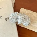 Dettaglio di una molletta a banana a fiori con eleganti rouches in tessuto bianco. - Floreale Bianco Pieghettato