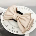 Dettaglio macro dell'elegante molletta a fiocco in raso champagne setoso - Albicocca