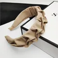 Dettaglio ravvicinato di un cerchietto in tessuto a pieghe kaki su una scatola regalo - Stile Nodo Increspato / Kaki