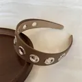 Dettaglio di una fascia punk in pelle marrone con occhielli in metallo argentato - Marrone
