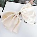 Dettaglio di un grande fermaglio a fiocco in raso avorio con rosa di metallo vintage - Bianco latte