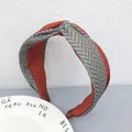 Primo piano di un cerchietto largo a spina di pesce con un elegante nodo intrecciato - Colore caramello