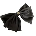 Dettaglio di un elegante fermaglio a fiocco in raso nero grande con rosa dorata centrale. - Nero