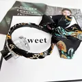 Primo piano della fascia in raso con stampa a catena retrò e un elegante fiocco nero - Stampa Catena Retro (Nero) / Nero