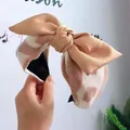 Primer plano de una elegante diadema ancha de punto con un gran lazo de satén beige decorativo. - Lazo de Punto de Corazón Caqui Claro