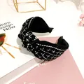 Close-up of black and white tweed knotted headband showing elegant retro textile texture - Black