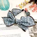 Close-up of vintage blue floral bow headband with brown piping on white background - Sky Blue Floral