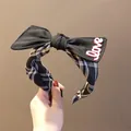 Dettaglio di un cerchietto con fiocco nero, motivo scozzese e scritta LOVE rosa - Fiocco Nero (TK21509) / Nero Opaco