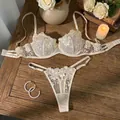 Detailansicht eines beigen Spitzen-Dessous-Sets mit Rosenstickerei auf Holzgrund. - S / Oberteil Und Unterteil / Aprikose