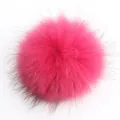 Primer plano de un pompon de piel de mapache teñido fucsia de 15cm con textura suave - Rosa rojo