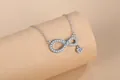Detailed macro shot of an elegant infinity symbol necklace featuring pavé heart zircon stones - Silver