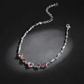 Macro detail showing heart-shaped red zircon stones on a silver-toned delicate bracelet - Red