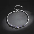 Close-up of silver-colored bracelet with purple heart zircons on a black background - Purple