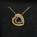 Elegant double heart pendant necklace in gold and silver tones on black background - Gold and Silver Two-Tone with White Rhinestone