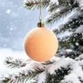 Palla di Natale floccata color pesca appesa a un ramo di pino innevato dettaglio immagine - nudo