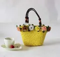 Detail van een gele strooien strandtas met levendige bloemen en kralen handgrepen - Geel