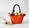 Detailweergave van oranje stro tas met kleurrijke zijden bloemen - Oranje
