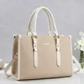 Close-up of minimalist beige handbag with gold hardware and elegant textured finish - Off White