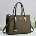Vista frontal de un elegante bolso de mano en cuero verde oliva con detalles plateados - Verde