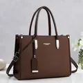 Primer plano de un elegante bolso tote retro de cuero marrón oscuro con detalles metálicos. - Café