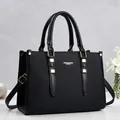 Detail of elegant black faux leather tote bag with gold-tone hardware and top handles - Black