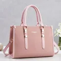 Elegant front view of a pink leather handbag featuring gold metal buckles and trim - Pink