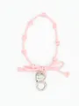Detail of pink woven wrist strap featuring a silver heart charm and bow knot - Pink