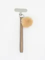 Detail view of the tan PU leather wrist strap with fluffy fur ball and phone tether tab. - Coffee