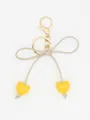 Detailed view of yellow heart charms and beige bow knot on a golden keychain pendant - Bright Yellow Heart With Beige Rope