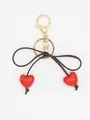 Detailed view of glossy red heart beads and brown bow knot on elegant gold keychain - Red Heart With Brown Rope