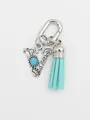 Detailed view of silver ethnic initial V bag charm with turquoise and blue tassel - Letter V