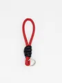 Detail view of a red and black PU leather woven wrist strap keychain on white bg. - Red and Black