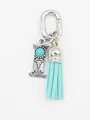 Close-up of ethnic style silver alphabet I charm with turquoise and blue tassel - Letter I