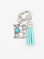 Close-up detail of vintage silver letter B charm featuring turquoise stone and teal tassel - Letter B