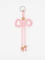 Detailed view of a hand-woven pink braided bow pendant with decorative beads and metal ring. - Pink