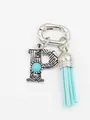 Close-up of a silver letter P bag charm with a blue turquoise stone and tassel - Letter P