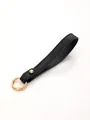 Close-up of black pebbled leather strap keychain with gold metal ring detail - Black