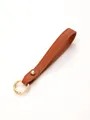 Detail view of a high-quality brown pebble leather keychain strap with a gold metal ring - Brown