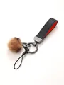 Close-up of leather keychain with fluffy faux fur ball and metallic hardware - Keychain Pendant / Black